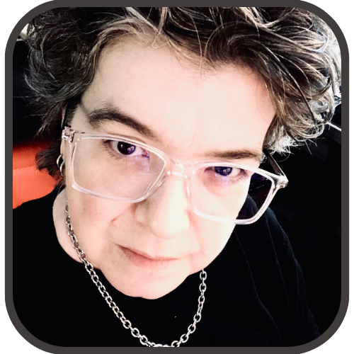 Kris Dresen, the writer and illustrator of GRACE (the graphic novel that Her Curve is based on), Kris has silver glasses and a chain and is wearing a black shirt. 